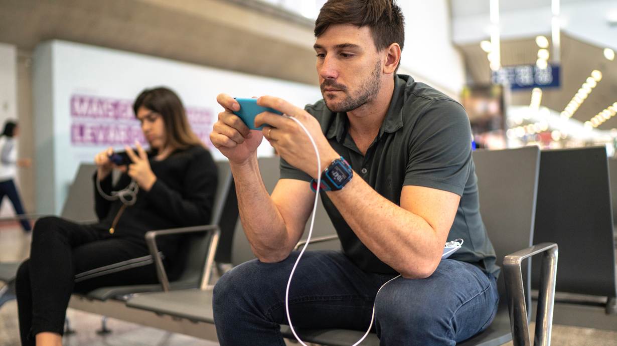 Man In Airport Enjoying 5G Gaming On Mobile Phone