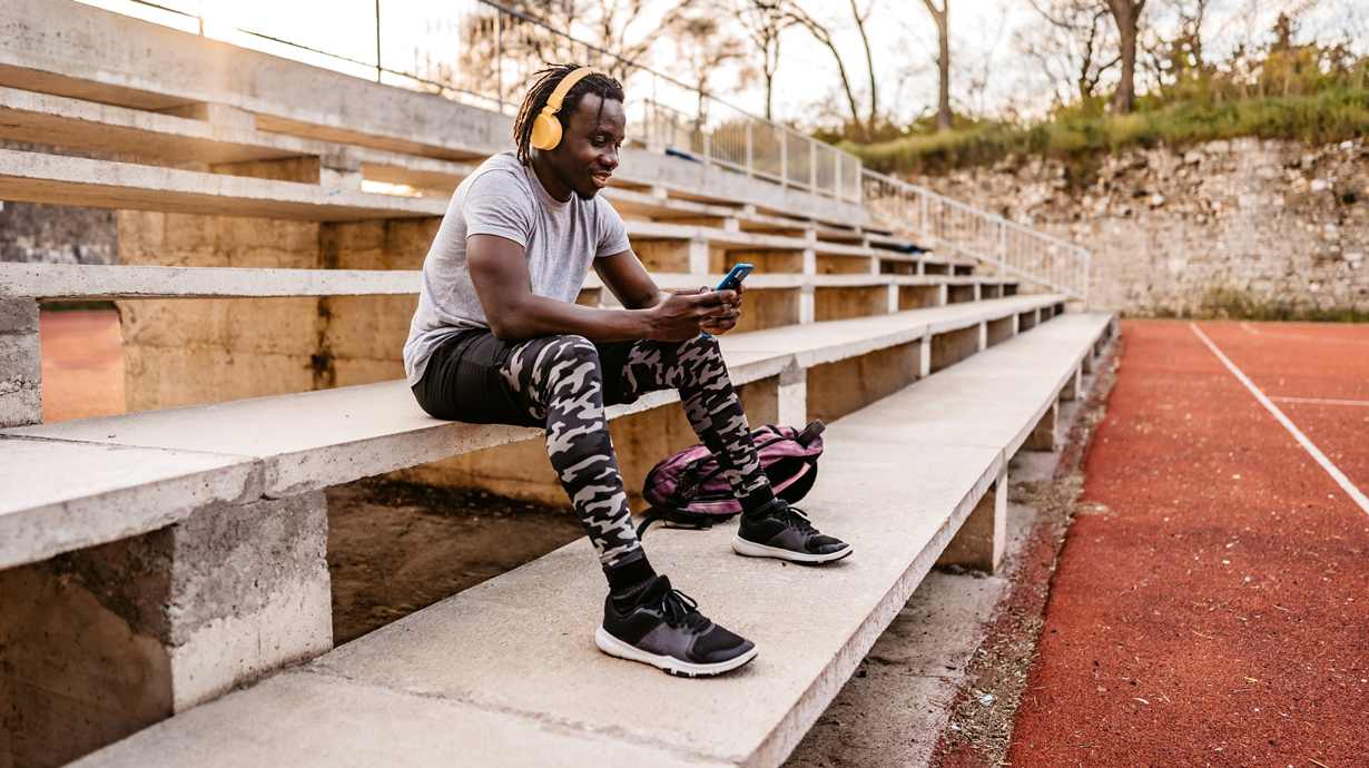 Man Sitting On Bleachers With Smartphone | How Fast Is 5G