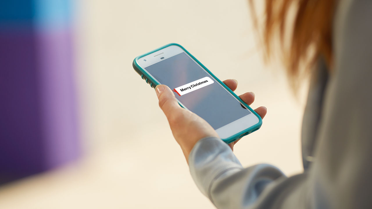 Person holding phone with screen saying Merry christmas