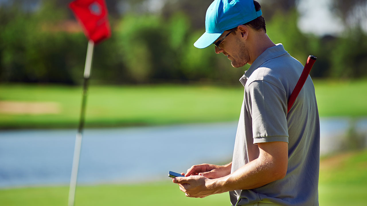 Man golfing looking at his phone