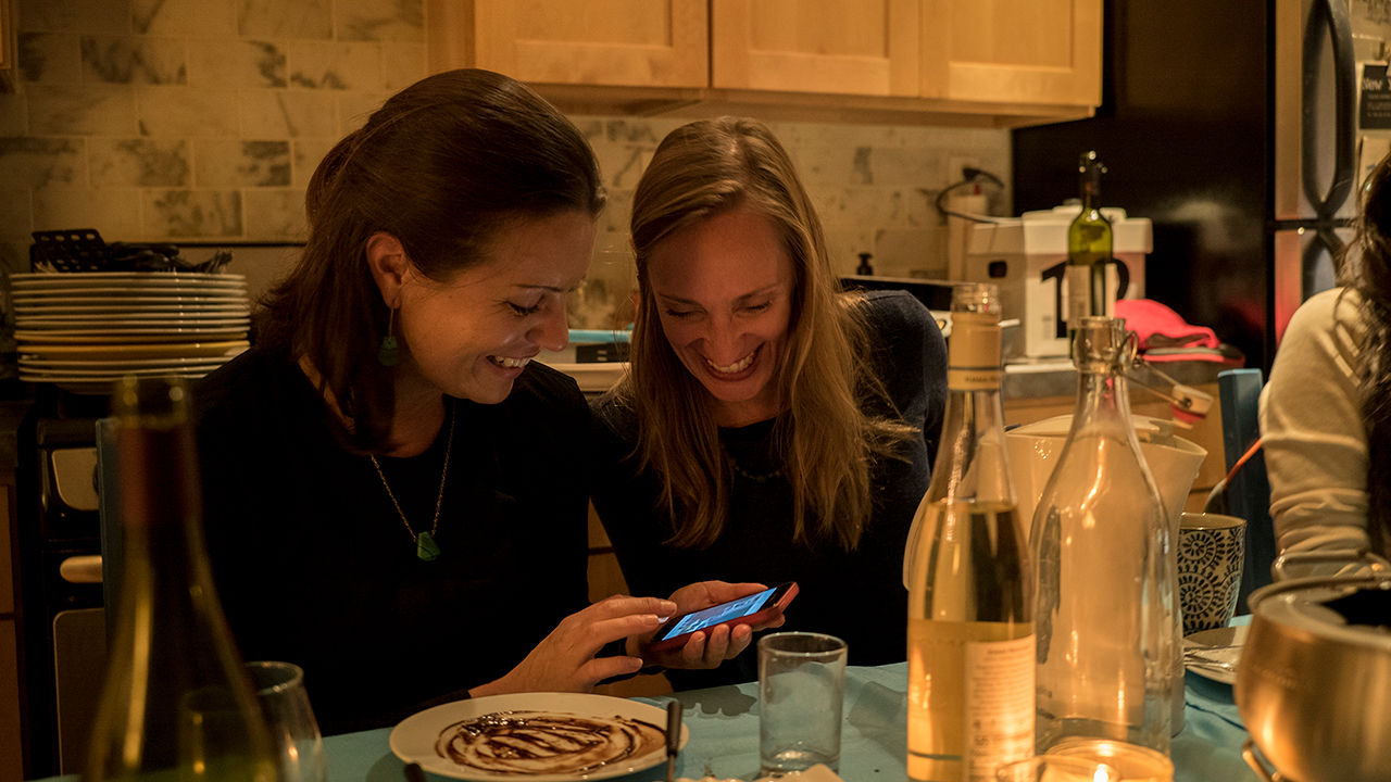 Two women looking at phone at kitchen table