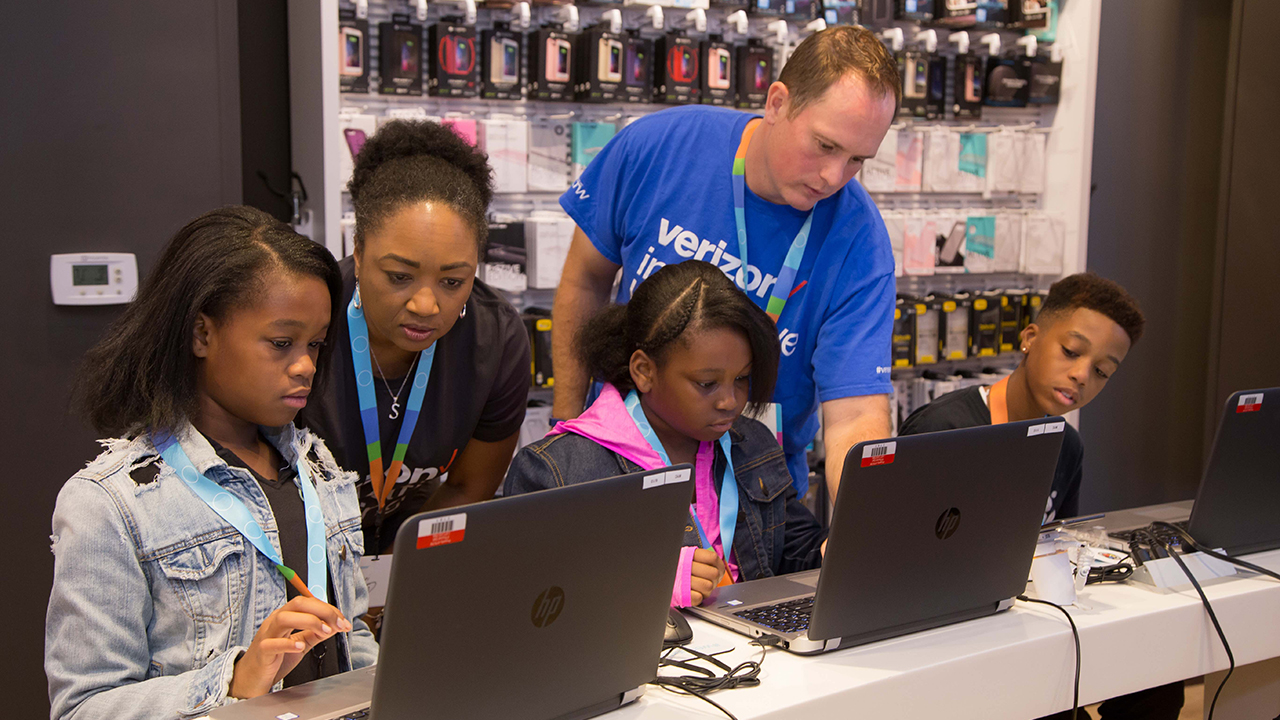 Instructor Justin Ryan and Verizon volunteer Sherri Salley help the students emote