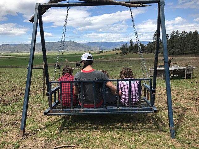 Girls on a swing looking out at farm