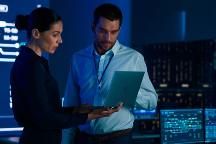 Security monitors reviewing data on laptop