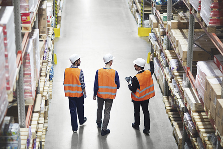 Group of warehouse workers walking through warehouse in reflective vests