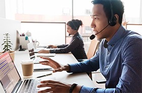 Two customer service agents assisting customers while talking on headsets