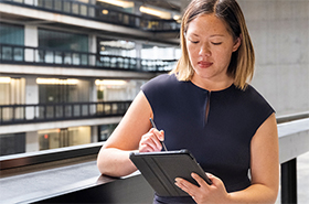 Woman using a tablet while standing on building balcony