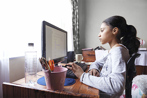 Teenage girl doing homework on a computer.
