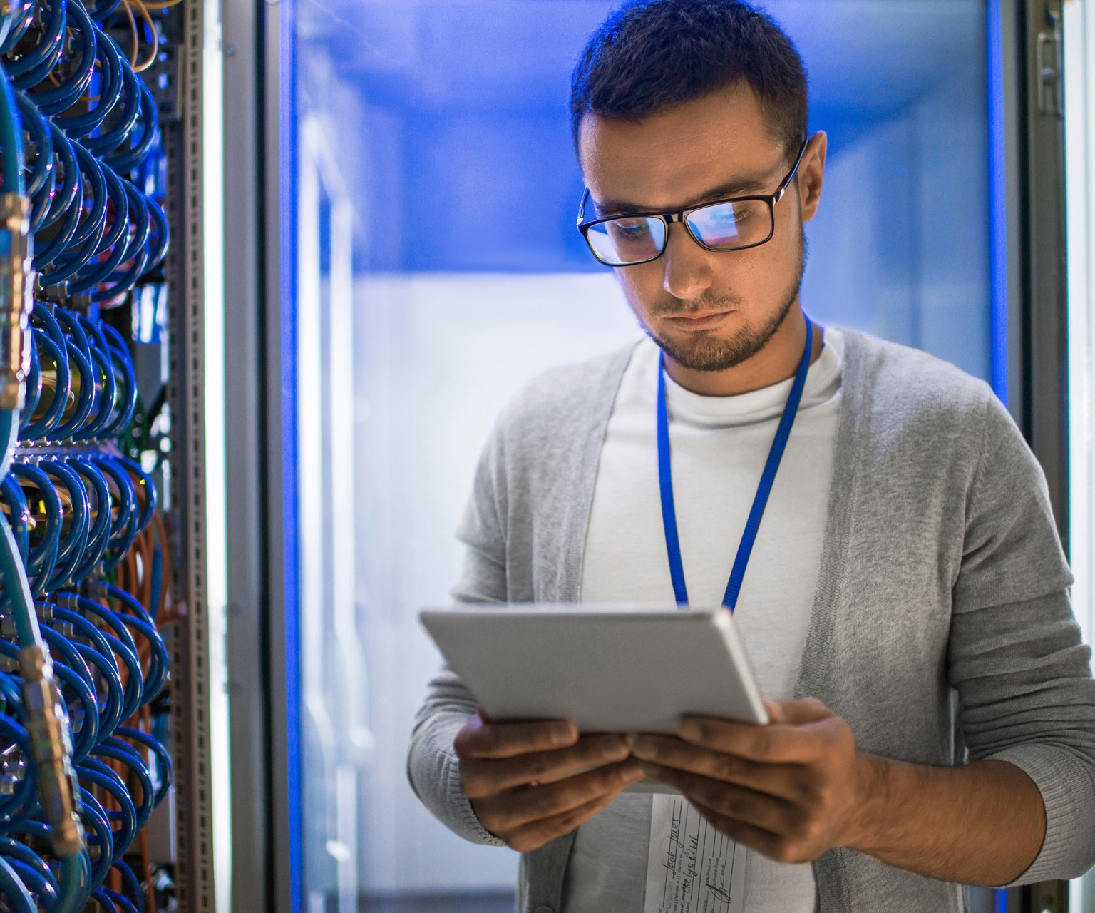 Man wearing glasses using tablet by cables