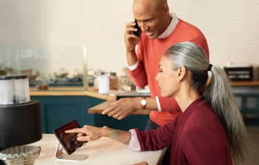 Woman and man on cellphone pointing to tablet