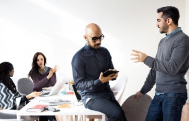 Man using a tablet while listening to a coworker