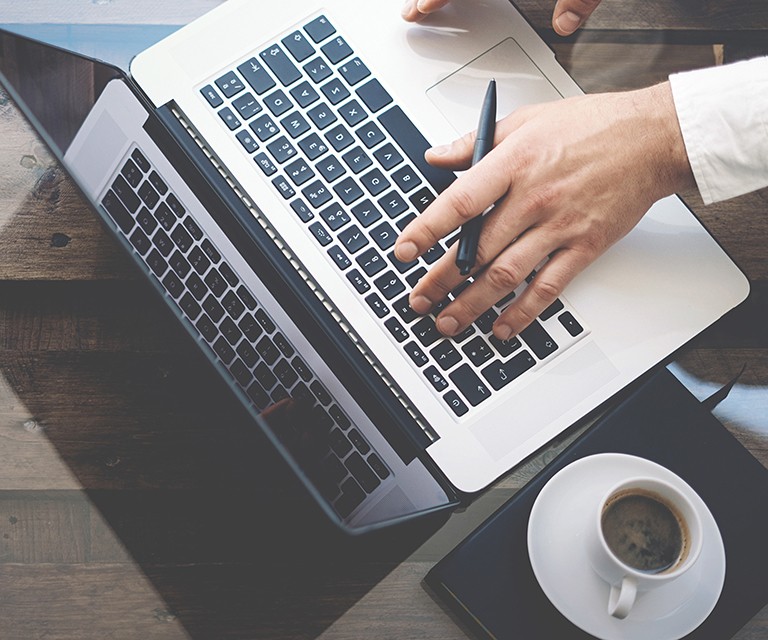 Overhead view of a person working on a laptop with a cup of coffee