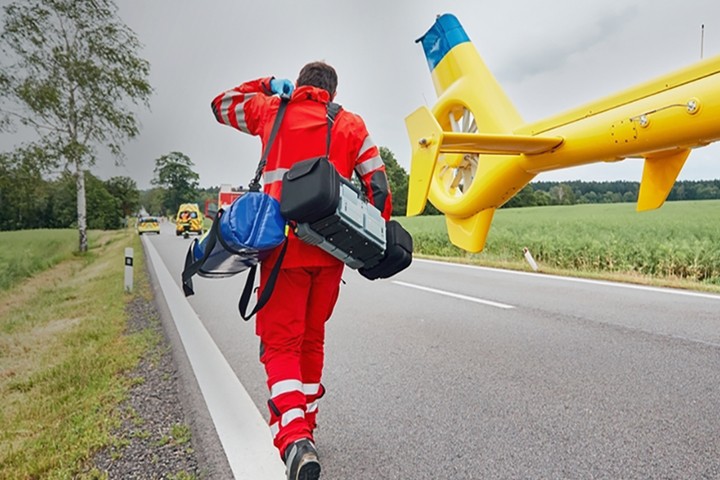 First responder with medical equipment running from helicopter