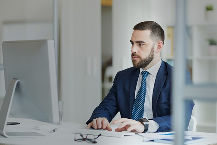 Man typing on keyboard while using a desktop computer in his work office