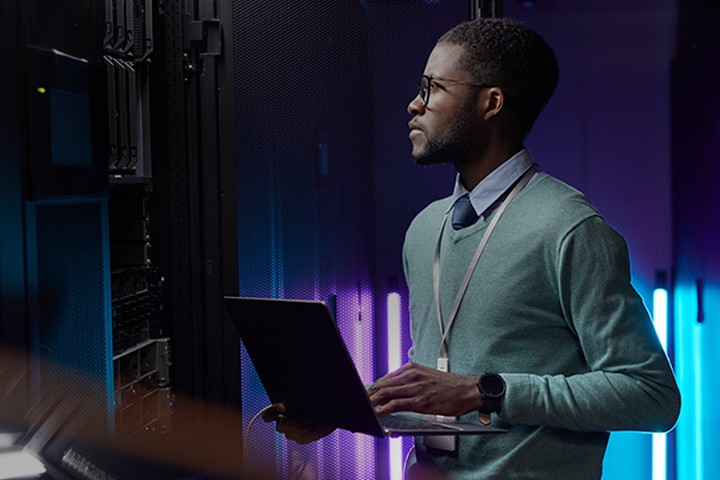 Man using laptop while monitoring servers in data room