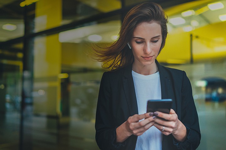 Woman checking smartphone while standing outside of office