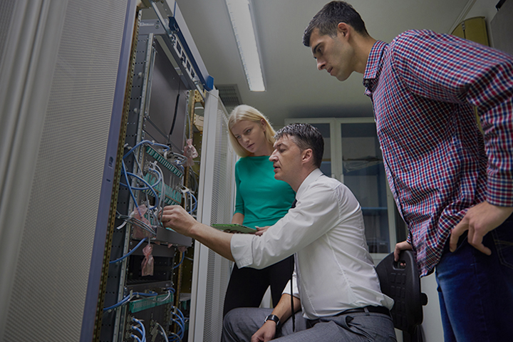 Three network engineer colleagues working in a server room