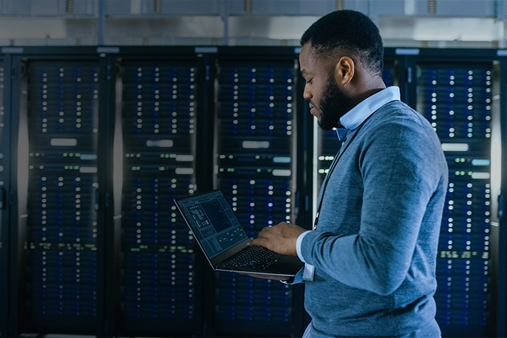 IT technician working in server room while holding a laptop