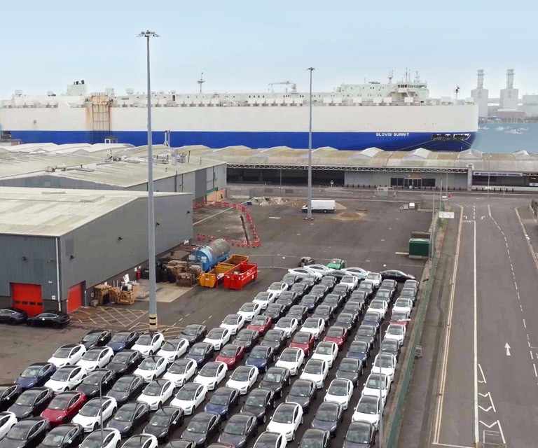 An aerial view of a portion of the Port of Southampton showing warehouses and a large area full of parked vehicles.