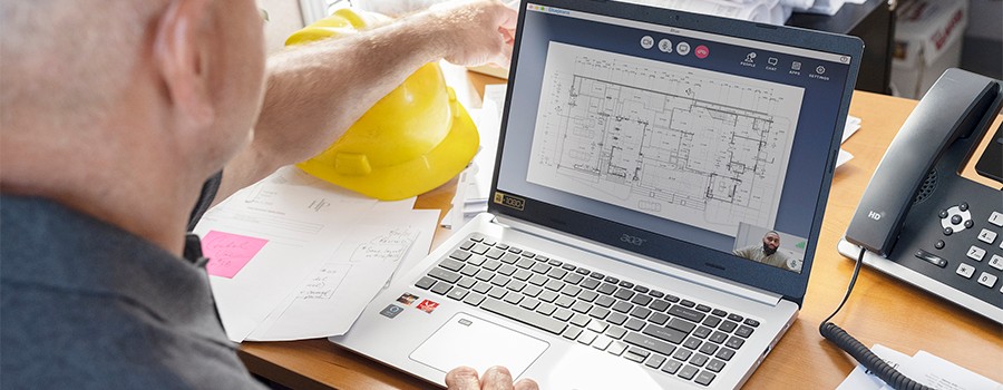 Construction project manager reviewing blueprints on a video conference via laptop