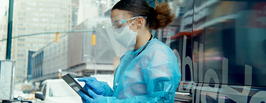 Mobile health nurse holding a tablet while standing outside of medical van