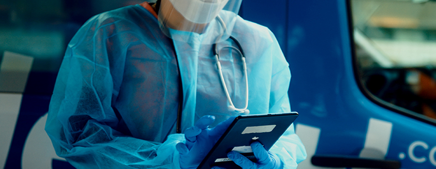Mobile health nurse holding a tablet while standing outside of medical van