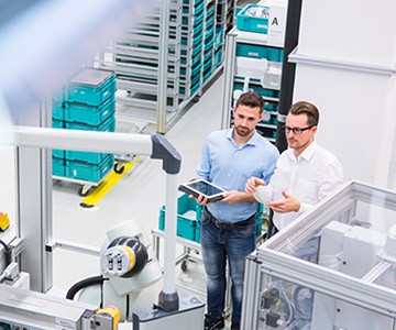 Two white men are in the lab, holding a device