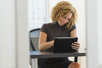 Woman sitting at a desk and typing on a tablet