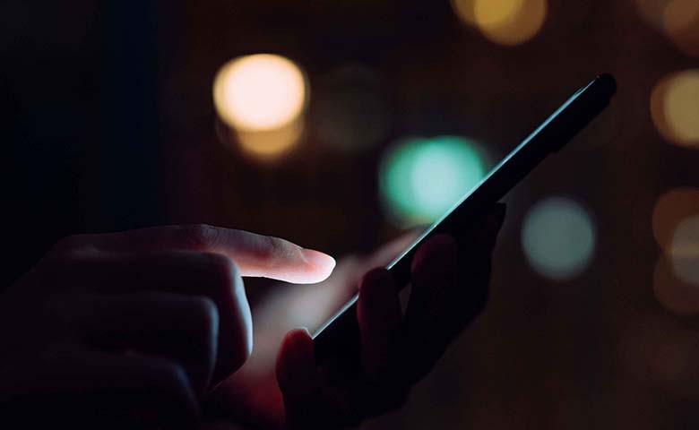 finger tapping a mobile in a dark room