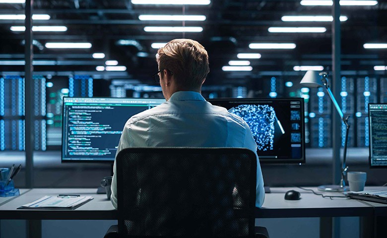 Professional IT Programer Working in Data Center on Desktop Computer with Two Displays, Doing Development of Software and Hardware. Displays Show Blockchain. Data Network Architecture Concept