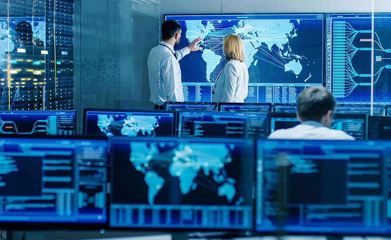 a man and a woman at the world map in a computer room