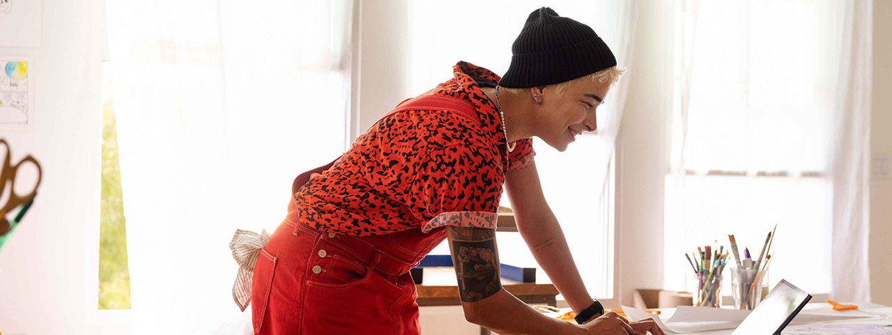 A lady in red clothes looking at laptop in workroom