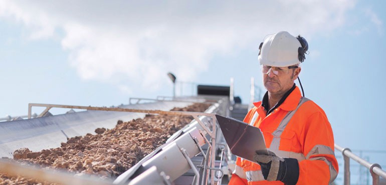 Man wearing hard hat using tablet on site