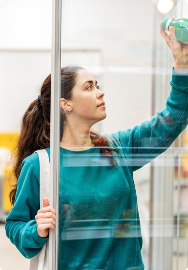 woman getting bottle from refrigerated section in store