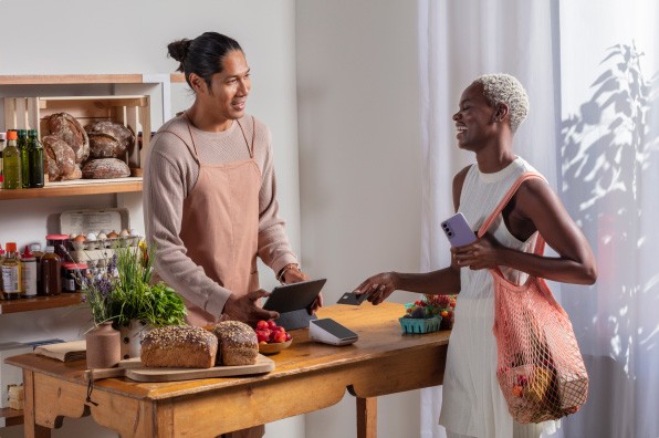 woman making a purchase from man using tablet as a register