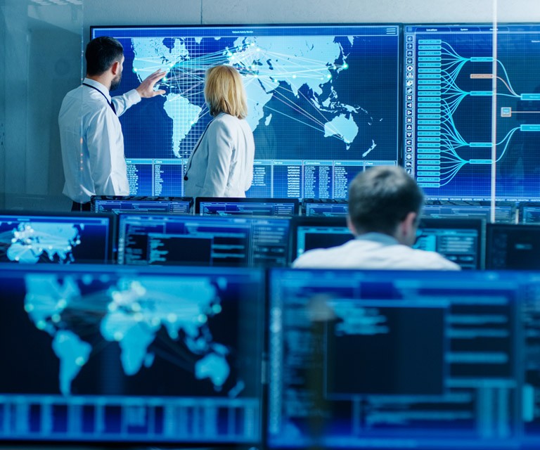 co-workers pointing at a world map on a large screen