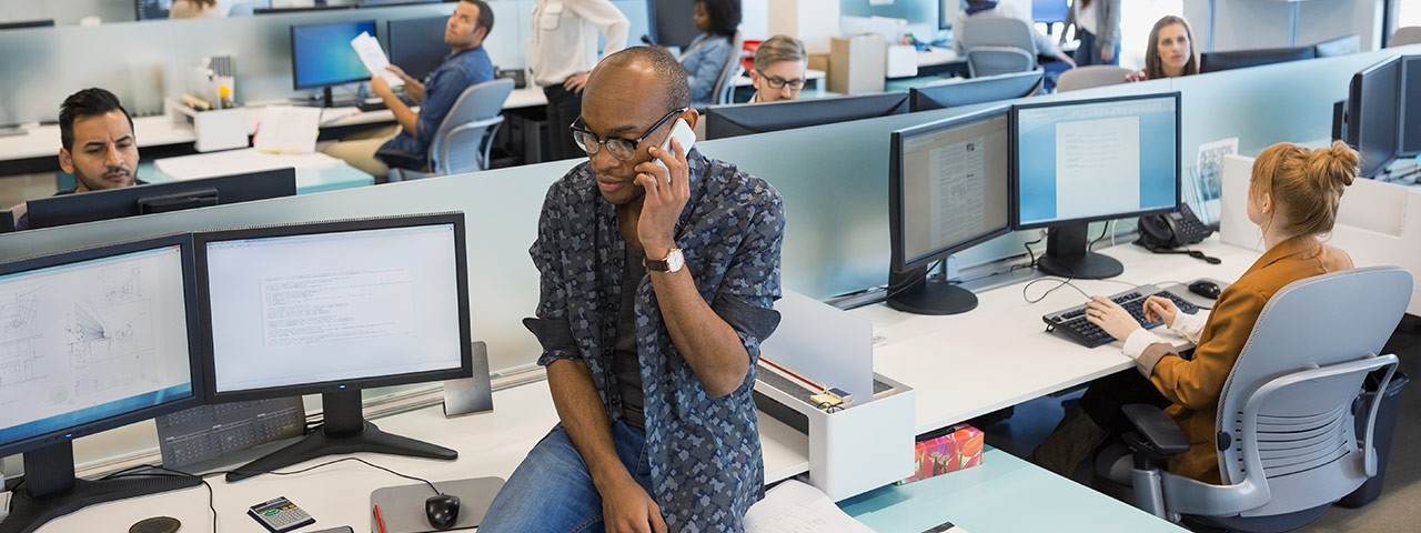 An office scene with a man talking on a telephone in the foreground