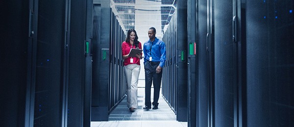 Two workers walk through a server room