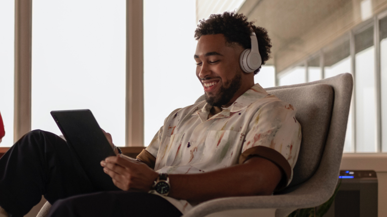 man wearing headphone looking at laptop smiling