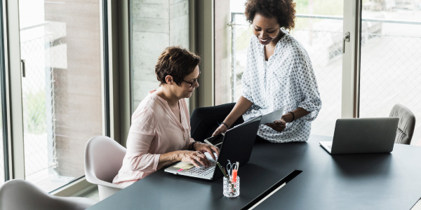 Two employees collaborating in front of a laptop