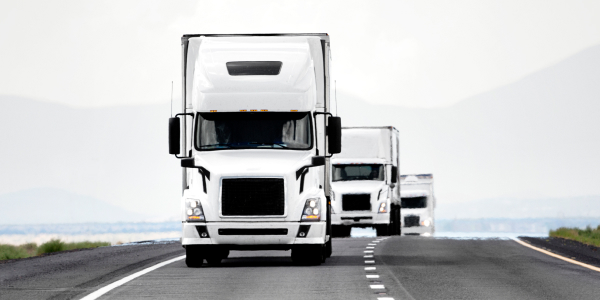 Three trucks driving down the road