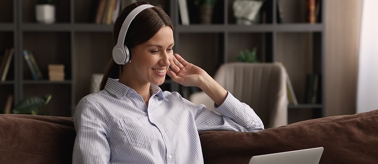 Happy young business lady in headphones holding video call meeting.