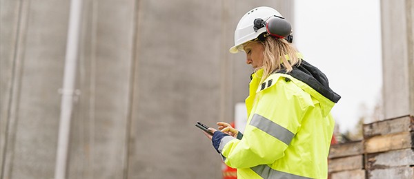 Woman in construction gear looking at her phone.