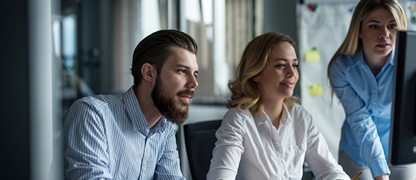 Two women and a man looking at a computer screen.