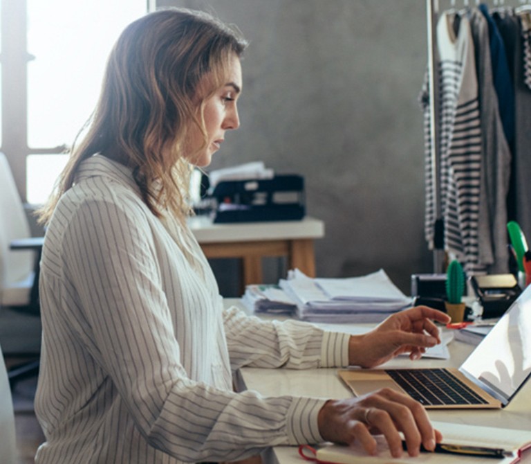 Woman using a laptop while sitting at desk in studio