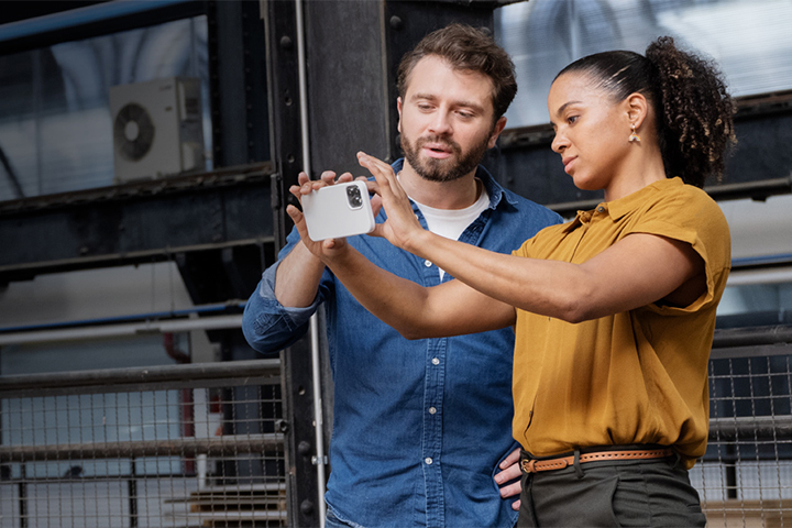 Woman and man using a smartphone to take photos within a warehouse factory