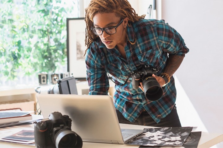 Man using a laptop to review images downloaded from digital camera