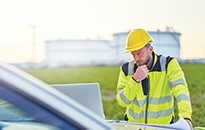 Man wearing hard cap construction helmet using laptop