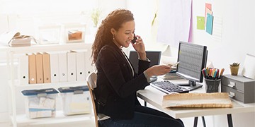 woman sitting at desk talking on mobile phone