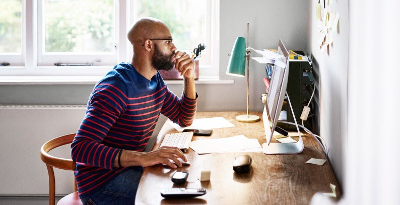 man sitting at desk looking at computer